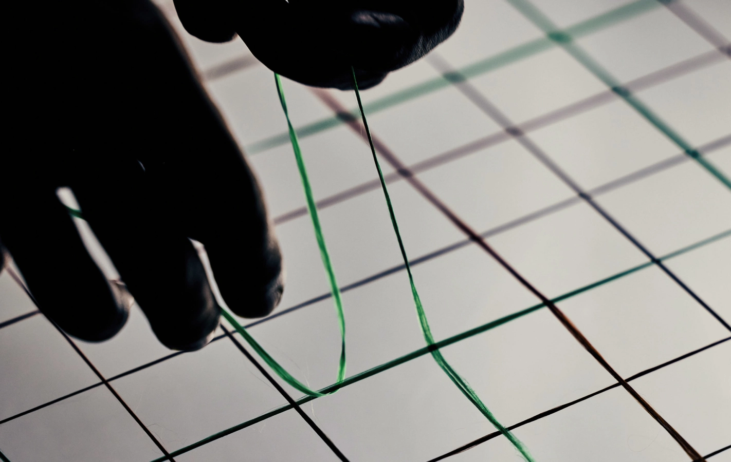 A green fiber being positioned by hand
